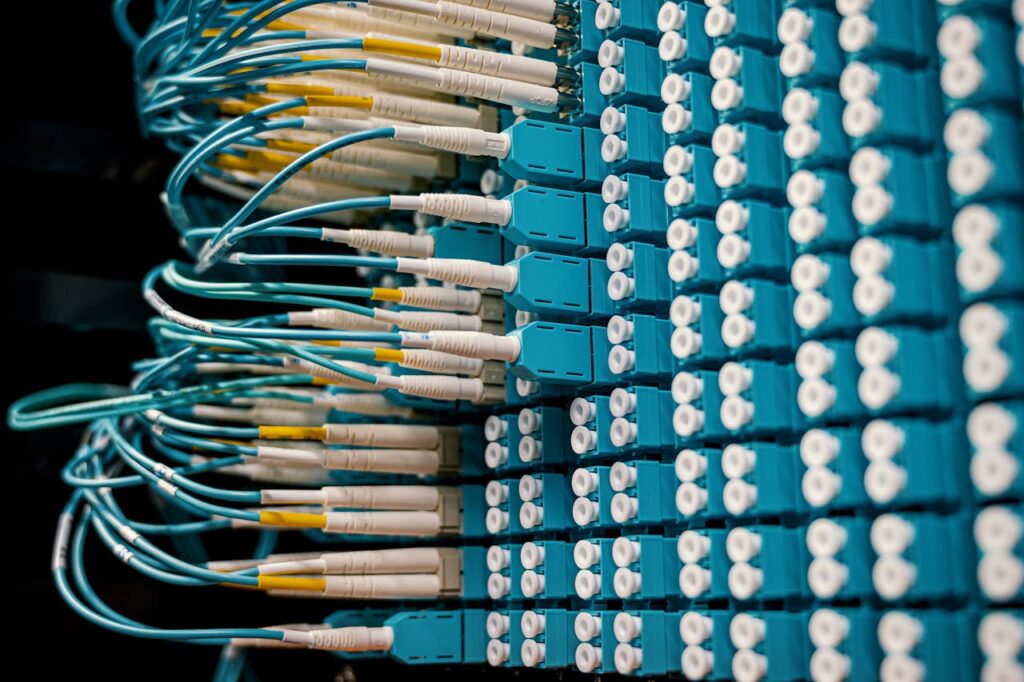 pexels-photo-4339335 Close-up of a network patch panel with connected blue fiber optic cables.